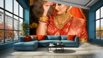 Portrait of very beautiful Indian bride holding betel leaf, Bengali bride in traditional wedding saree with makeup and heavy jewellery in studio lighting indoor Wall mural