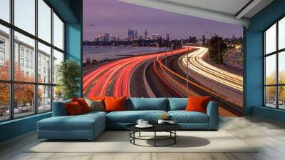 Winding Freeway at Night with Light Trails and City in background Wall mural