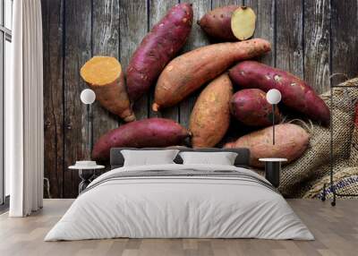 Mix of sweet potatoes with sack over wooden background Wall mural