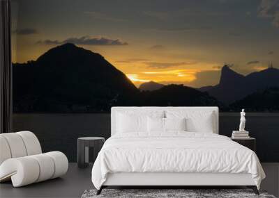 Dusk on the beach of San Francisco, Niteroi, Rio de Janeiro, Brazil. The sky is orange, the sea calm with the sun reflecting in the sea; you can see the silhouette of the mountains of the city of Rio. Wall mural