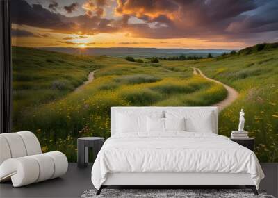 Winding path cuts through golden field under vibrant sky with scattered clouds, leading towards sun peeking at horizon. Lush greenery flanks trail, dotted with wildflowers landscape background, Wall mural