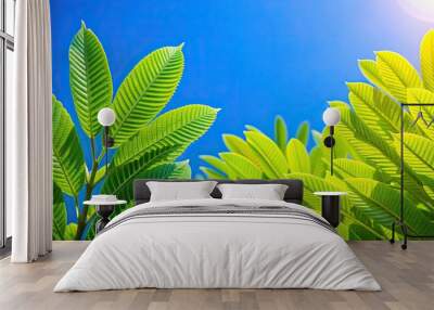 Vibrant green plant leaves contrast against a clear blue sky background, nature, foliage, vibrant, green, sharp, plant, leaves Wall mural