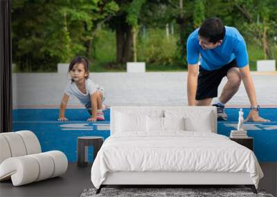 Asian father teaching daughter how to prepare running from starting line, concept of sport and excercise in happy family lifestyle. Wall mural