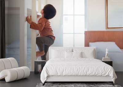 Asian little toddler boy is trying to climb up the ladder of bunk bed in the bedroom. Concept of childhood, kid development, physical activity, muscle, playful, learning, life skill for children. Wall mural