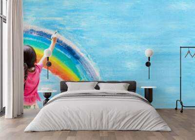 banner of unidentified little girl is painting the colorful rainbow and sky on the wall and she look Wall mural