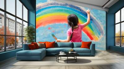 Unidentified little girl is painting the colorful rainbow and sky on the wall and she look happy and funny, concept of art education and learn through play activity for kid development.	 Wall mural