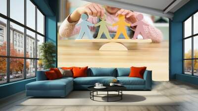 Unidentified little girl is trying to balance the people model on the wooden scale, concept of homeschool, montessori, learning, education and conceptual of equality, diversity, fairness. Wall mural