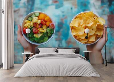 One hand holding bowl of vegetable salad, other holding chips. Healthy natural organic fresh vegetarian food vs unhealthy processed fast junk food. Lunch or snack decision Wall mural