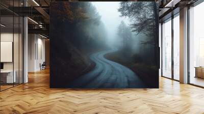 A spooky forest, shrouded in mist, with a dark road winding through it. The trees look eerie, perfect for a Halloween night. Wall mural