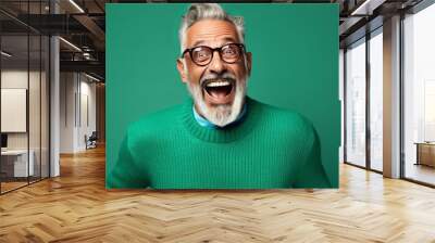 Older man in a green pullover and glasses in a picture of retirement against a blue color background. Wall mural