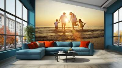 Summer vacations. Happy family is holding hands running on the beach at sunset. Father and mother and little children are having fun on a tropical beach. Wall mural