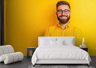 A cheerful man in a yellow shirt and glasses stands with arms crossed against a bright yellow background. Wall mural