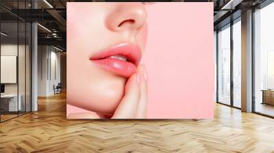 Close-up of a woman's face highlighting soft lips and smooth skin against a pastel background, emphasizing beauty and elegance. Wall mural