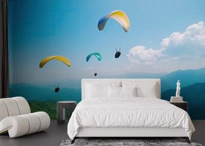 Colorful paragliders soaring above mountains under a bright blue sky, showcasing adventure and freedom in nature. Wall mural