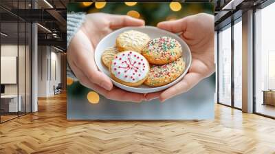 Two hands present a plate of decorated cookies, symbolizing warmth and festive joy during the holiday season. Wall mural