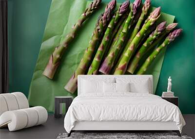 Bunch of fresh asparagus on green paper background, top view. 
 Wall mural