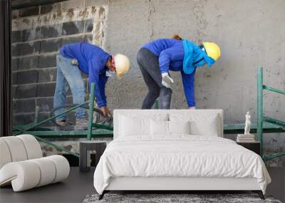 Plasterers using and operating sprayer mortar equipment machine for spraying mortar concrete cover brick wall and plastering for the decoration finishing work at the construction site Wall mural