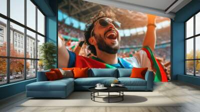 A jubilant young man, with his arms raised high, joyfully shouting and showing his excitement with a triumphant gesture at a soccer game. AIG41 Wall mural