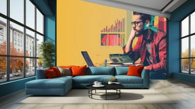 A man wearing glasses is sitting at a desk and looking at a laptop There are some books and papers on the desk The background is yellow AIGZ01 Wall mural