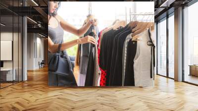 Beautiful woman shopping for clothes at retail apparel shop in the shopping mall. Modern trade lifestyle. Wall mural