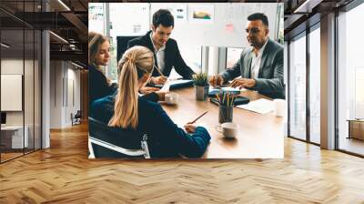 Businessman executive in group meeting discussion with other businessmen and businesswomen in modern office with coffee cups and documents on table. People corporate business working team concept. uds Wall mural