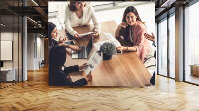 Businesswoman in group meeting discussion with other businesswomen colleagues in modern workplace office with laptop computer and documents on table. People corporate business working team concept. Wall mural