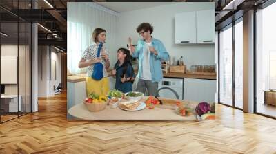 Caucasian skilled father, mother and asian daughter making breakfast while dancing together. Skilled mom playing ukulele while preparing vegetable at modern kitchen. Healthy food concept. Pedagogy. Wall mural