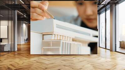 Closeup image of skilled architect engineer hand pointing at house model to measure house length. Asian project manager hand using pencil marking at architectural model. Business design. Manipulator. Wall mural