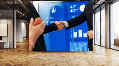 Closeup office worker shake hand business team leader manager for strong teamwork in office to promote harmony concept after successful agreement or meeting with dashboard report on screen background. Wall mural