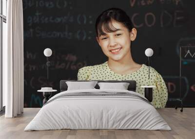 Cute happy girl smiling to camera while standing at blackboard with engineering prompt or coding, programing system written in STEM technology classroom. Smart student looking at camera. Edification. Wall mural