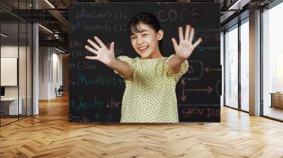 Cute happy girl waving to camera while standing at blackboard with engineering prompt or coding, programing system written in STEM technology classroom. Smiling student looking at camera. Edification. Wall mural