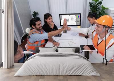 Diverse group of civil engineer and client celebrate and high five after make successful agreement on architectural project, reviewing construction plan and building blueprint at meeting table.Prudent Wall mural