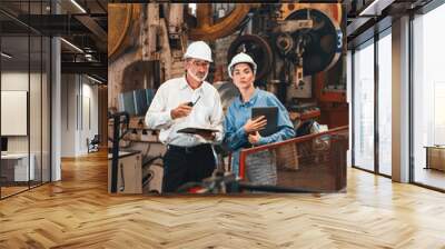 Factory engineer manager with assistant using laptop to conduct inspection of steel industrial machine, exemplifying leadership as machinery engineering inspection supervisor in metalwork manufacture. Wall mural