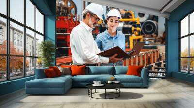 Factory engineer manager with assistant using laptop to conduct inspection of steel industrial machine, exemplifying leadership as machinery engineering inspection supervisor in metalwork manufacture. Wall mural