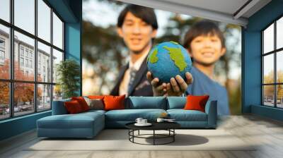 Focus Earth with blurred asian boy and businessman holding globe together as Earth day concept as corporate social responsible to make greener environmental for sustainable future generation. Gyre Wall mural