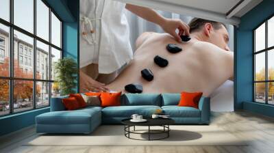 Hot stone massage at spa salon in luxury resort with day light serenity ambient, blissful man customer enjoying spa basalt stone massage glide over body with soothing warmth. Quiescent Wall mural