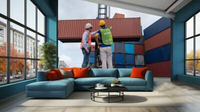 Industrial worker works with co-worker at overseas shipping container yard . Logistics supply chain management and international goods export concept . Wall mural