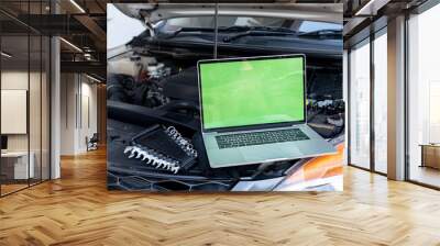 Laptop computer on car hood for engine diagnostic. Car garage repair service concept. Wall mural