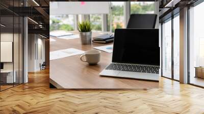 Laptop computer with opened lid on table in meeting room of office workspace. Wall mural