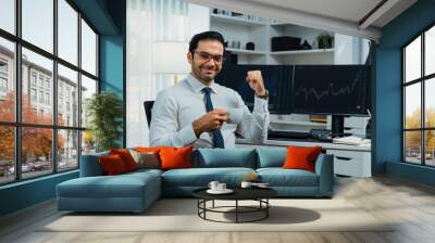 Profile of successful in trader businessman looking at camera with two stock exchange investment screens with raising fist up and thumb up in dynamic financial technology graph stock market. Surmise. Wall mural