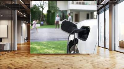 Progressive parent have returned from picking up daughter at school with concept of electric vehicle and renewable energy, charging station for EV car at home. Alternative eco transportation. Wall mural