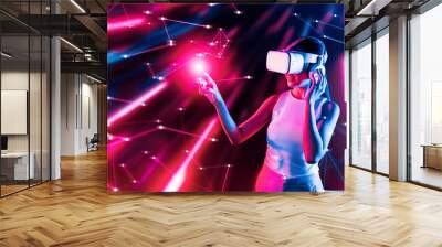 Smart female standing in cyberpunk style building in meta wear VR headset connecting metaverse, future cyberspace community technology, Woman use finger touching virtual reality object. Hallucination. Wall mural