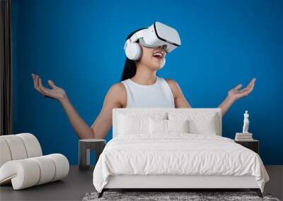 Smart female standing with blue background wearing VR headset connecting metaverse, futuristic cyberspace community technology. Elegant woman excited seeing generated virtual scenery. Hallucination. Wall mural