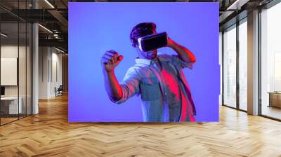 Smart man wearing VR glass and smashing or punching at camera. Professional sport gamer boxing and moving gesture in metaverse or virtual world while using digital technology innovation. Deviation. Wall mural