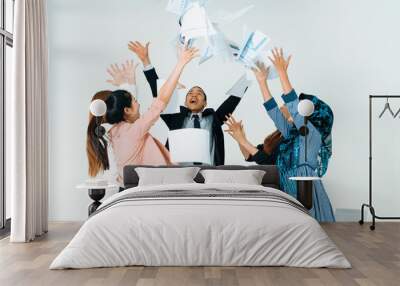 Smiling business people having fun by throwing papers in the air celebrating business success in the modern office. Happy workplace and casual career company concept. uds Wall mural