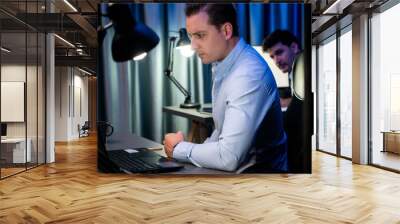 Stressful businessman waiting email sending back for deadline project overwork load at night time, supported by business partner to solve issue problem on laptop at neon light of workplace. Sellable. Wall mural