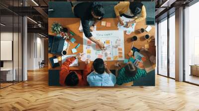 Top down aerial view of business team making scrum task board at meeting room. Group of people writing at paper and sticky notes for making kanban board to manage work flow. Top view. Convocation. Wall mural