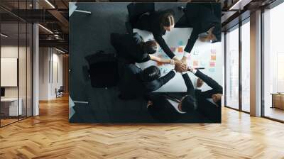 Top down aerial view of professional investor team putting hand together. Skilled diverse business team to celebrate successful project at meeting table with sticky note. Love and unity. Directorate. Wall mural