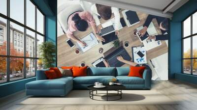 Top view of businessman executive in group meeting with other businessmen and businesswomen in modern office with laptop computer, coffee and document on table. People corporate business team concept. Wall mural