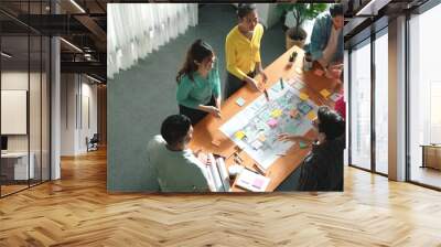 Top view of civil engineer team writing at blueprint at meeting table with color palettes. Group of smart diverse people planning and taking a note while manager looking at project plans. Symposium. Wall mural